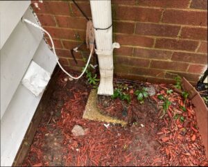 Home inspection photo of a downspout discharging at foundation, Warrenton, VA.