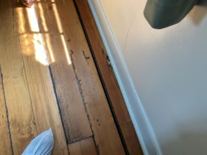 Severe floor sloping and shifting floorboards near a wall, indicating potential joist or foundation settling in Loudoun, VA.